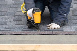Workman using pneumatic nail gun install tile on roof of new house under construction Roofer replacing damage roof Geo City